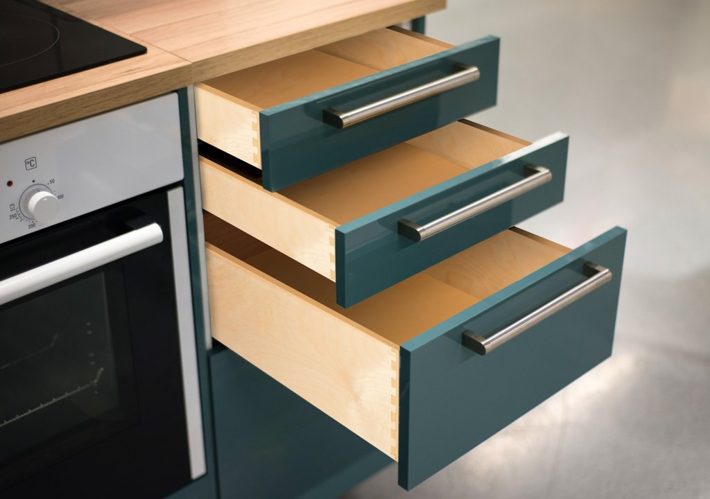 A model kitchen showing in detail drawers with a teal blue front and wood colored interior