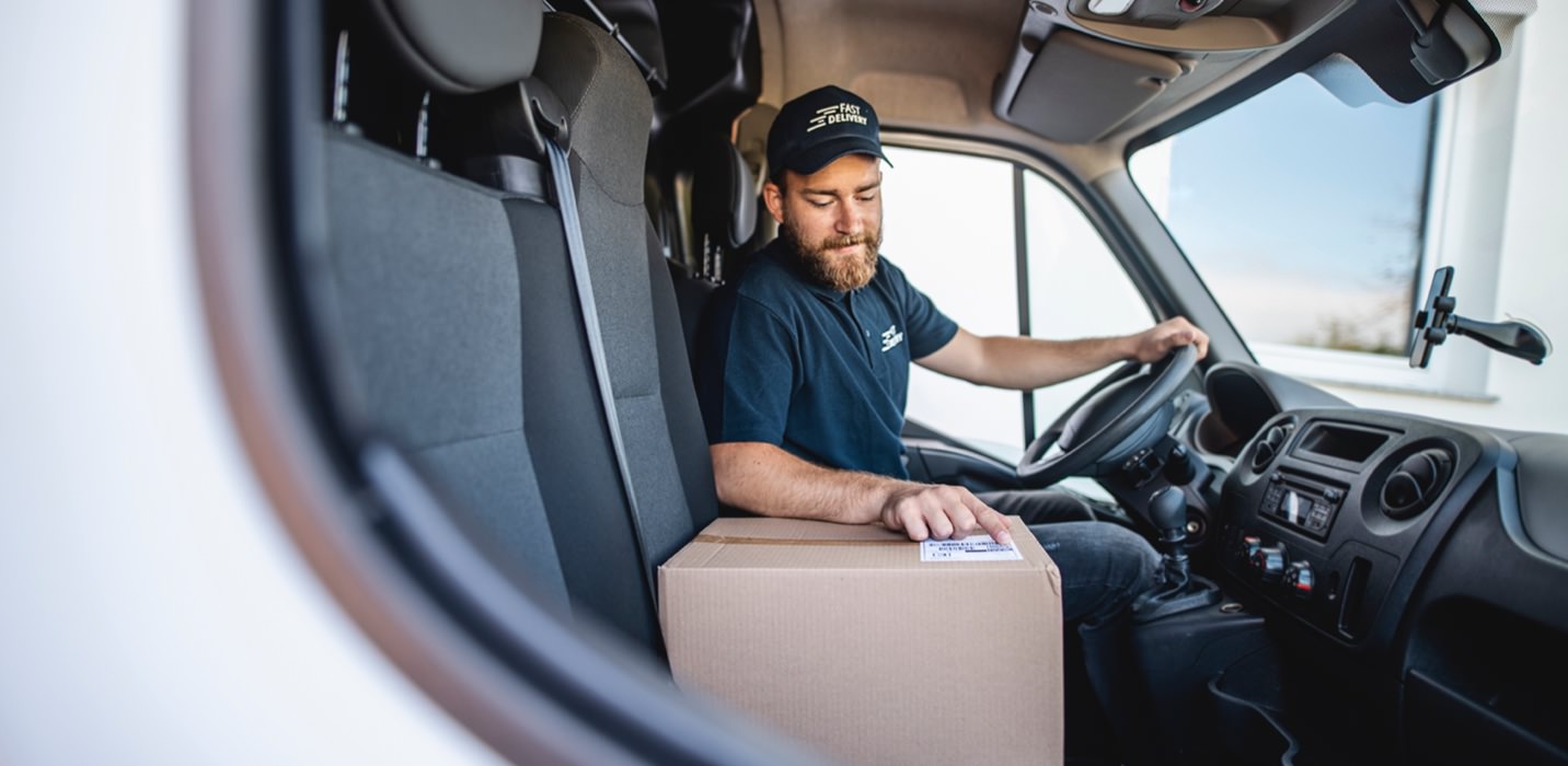 a delivery man reads an address label in a van with custom panels