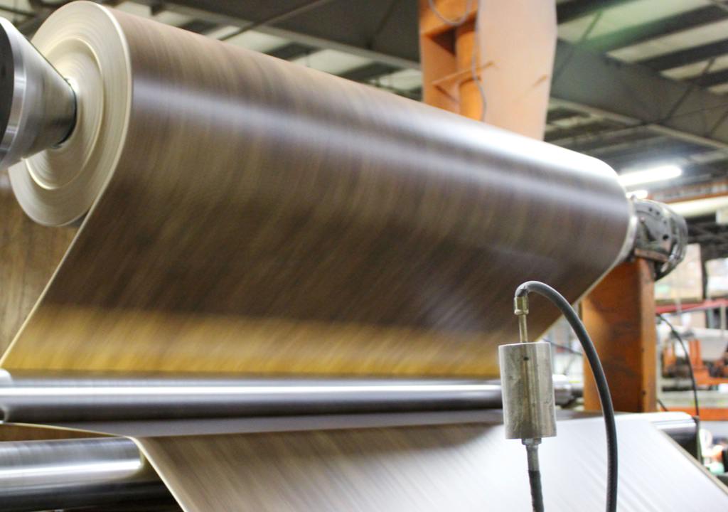 A machine feeds laminate material through large rollers