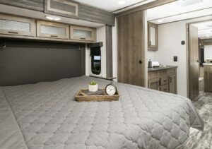 The bedroom in an RV with a laminate bed and cupboards