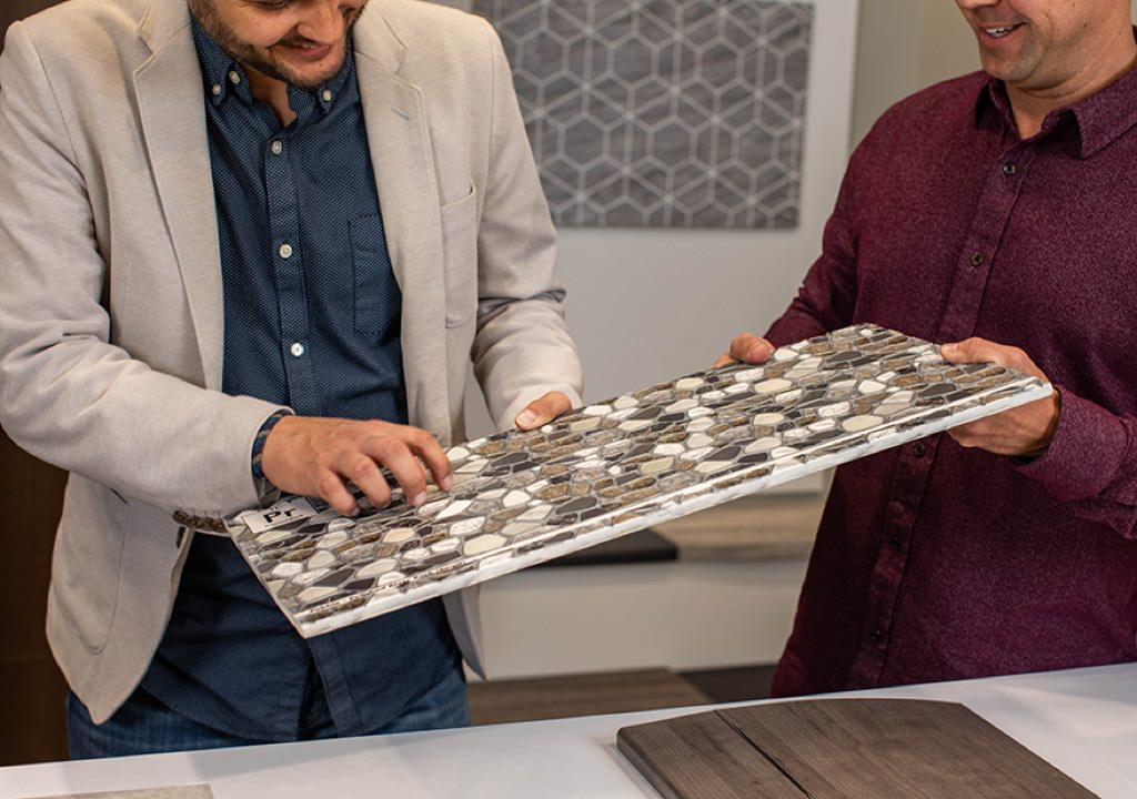 two men look at a sample of laminate stone tile made by Genesis Products