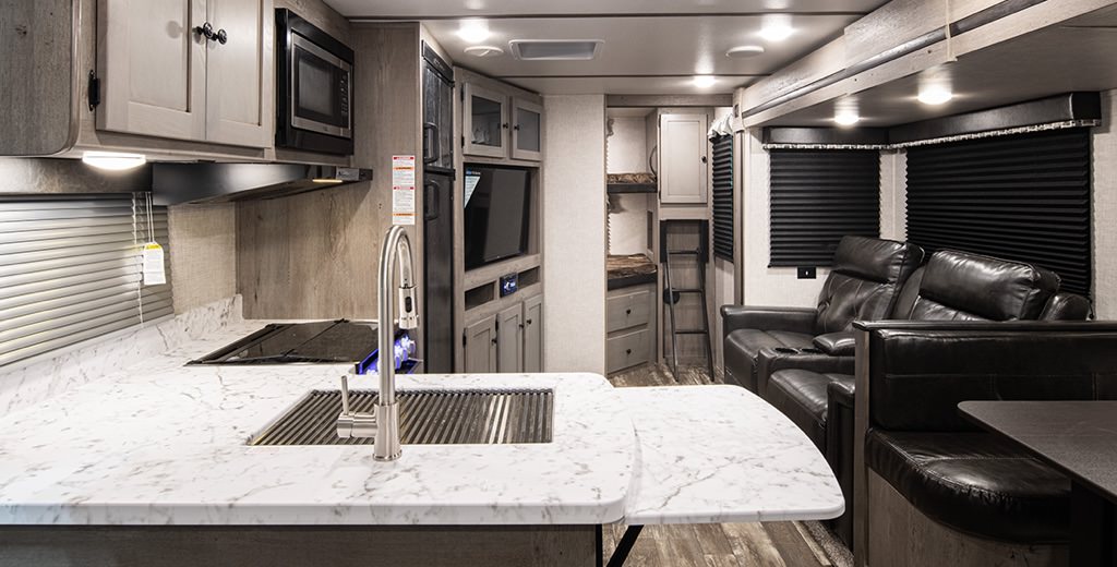 A sample RV kitchen furnished with a laminate countertops and cupboards