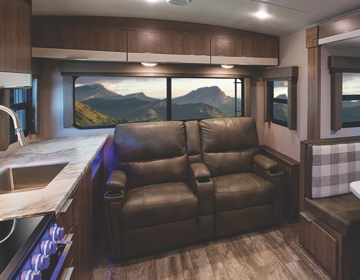A livingroom in an RV has multi-toned doors on the cabinets