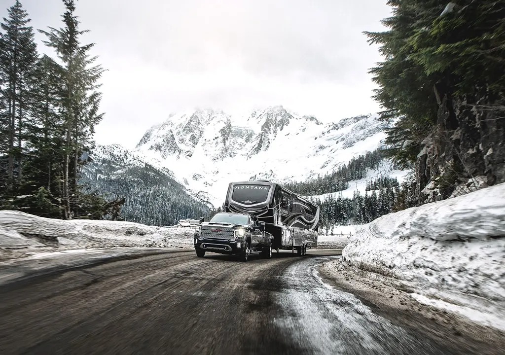 A truck hauls an RV on a snowy mountain road